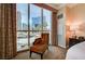 Comfortable chair near floor-to-ceiling windows offering city views in this contemporary bedroom at 145 E Harmon Ave # 201, Las Vegas, NV 89109