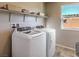 This laundry room has a side-by-side washer and dryer with built-in shelving near a window at 2674 Duneville St, Las Vegas, NV 89146