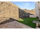 Spacious backyard featuring artificial turf, patio area, and a rock wall backdrop at 350 Solitude Peak Ln, Henderson, NV 89012