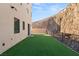 Side yard showcases artificial turf and a contemporary exterior against a natural rock formation at 350 Solitude Peak Ln, Henderson, NV 89012
