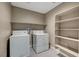 Well-lit laundry room with washer, dryer, and shelving at 3736 Paseo De Paz Ave, Las Vegas, NV 89115