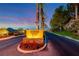 Exclusive community entrance with vibrant flowers, mature palm trees, and mountain views at sunset at 5 Via Ravenna Ct, Henderson, NV 89011