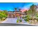 Elegant two-story home featuring a stone archway, tiled roof, two-car garage, and lush landscaping at 5 Via Ravenna Ct, Henderson, NV 89011