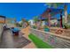 Multi-tiered backyard featuring a pergola, stone retaining wall, artificial turf, dining table, and lounge furniture at 516 Arizona St, Boulder City, NV 89005