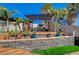 Outdoor lounge area with a built-in fireplace, pergola, seating, desert landscaping, and stone retaining wall at 516 Arizona St, Boulder City, NV 89005