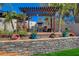 Relaxing outdoor lounge space with a built-in fireplace, pergola, seating, stone retaining wall, and desert landscaping at 516 Arizona St, Boulder City, NV 89005