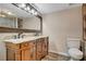 Bathroom featuring a double sink vanity with decorative wood trim, granite countertop, and adjacent toilet at 516 Arizona St, Boulder City, NV 89005