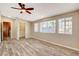 Bedroom featuring wood-look floors, a ceiling fan, and bright windows, adjacent to a walk-in closet at 516 Arizona St, Boulder City, NV 89005