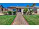 Charming home featuring a well-manicured lawn, mature trees, and a welcoming brick pathway at 516 Arizona St, Boulder City, NV 89005