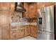 Kitchen with stainless fridge, wood cabinets, brick backsplash, and granite countertops at 516 Arizona St, Boulder City, NV 89005