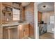 Gourmet kitchen with stainless dishwasher, brick accent wall, wood shelving, and laundry access at 516 Arizona St, Boulder City, NV 89005