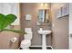 Stylish half bathroom with modern fixtures, pedestal sink, and stylish décor and a big green plant at 5662 Escamilla Rd, Las Vegas, NV 89135