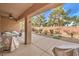 A covered back patio with outdoor seating overlooks a gravel-covered backyard with a block wall and some shrubs at 6128 Forest Pony Ave, Las Vegas, NV 89122