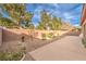A concrete patio runs along a brick wall in a backyard with gravel and desert landscaping at 6128 Forest Pony Ave, Las Vegas, NV 89122