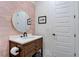 Modern bathroom with a rustic wood vanity, round mirror, and white door at 6265 Iron Mountain Rd, Las Vegas, NV 89131