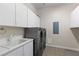 Bright laundry room showcasing modern stacked washer/dryer, ample white cabinetry, and sink with fixtures at 7288 Olsen Farm St, Las Vegas, NV 89131