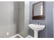 Stylish powder room with pedestal sink, wooden framed mirror, and modern gray wall paint at 7288 Olsen Farm St, Las Vegas, NV 89131