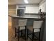 Stylish kitchen island featuring tile countertops, seating, stainless steel refrigerator, and modern white cabinetry at 7904 Greycrest Ct # 104, Las Vegas, NV 89145