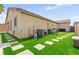 Manicured backyard featuring artificial grass and concrete tile stepping stones to the home at 820 Wintersweet Rd, Henderson, NV 89015
