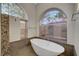 Luxurious bathroom featuring a soaking tub with arched window and a walk-in shower at 8470 S Pioneer Way, Las Vegas, NV 89113