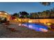 Stunning pool area with custom waterfall feature, surrounded by lush greenery and lighting at 8470 S Pioneer Way, Las Vegas, NV 89113