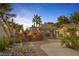 Backyard with beautiful landscaping, outdoor fireplace, palm trees, and manicured bushes at 9 Quail Run Rd, Henderson, NV 89014