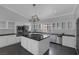 Stylish kitchen with black countertops, white cabinets, stainless steel appliances, and central island with cooking range at 9 Quail Run Rd, Henderson, NV 89014