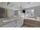 Main bathroom featuring double sinks, a large mirror, and a luxurious soaking tub at 9 Quail Run Rd, Henderson, NV 89014
