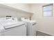 Well-lit laundry room featuring new, modern side-by-side washer and dryer units with a shelf at 9006 Cedar Door Ave, Las Vegas, NV 89148