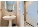 Cozy powder room featuring pedestal sink, round mirror, and tile flooring at 9465 Milkweed Canyon Ave, Las Vegas, NV 89166