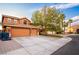 Expansive driveway leading to a three-car garage, complemented by mature trees and desert landscaping at 1017 Fairbury St, Henderson, NV 89052
