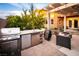 A backyard patio featuring an outdoor kitchen, grill, mini-fridge, and relaxing chairs at 1017 Fairbury St, Henderson, NV 89052