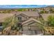 Aerial view of a two-story home featuring a two-car garage with lush landscaping at 10385 Grassyrock Ct, Las Vegas, NV 89129