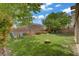 Well-maintained backyard featuring a lush lawn, mature trees, patio, brick perimeter wall and seating area at 10385 Grassyrock Ct, Las Vegas, NV 89129
