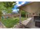 Relaxing backyard featuring a covered patio, mature trees, lush green grass, and lounge chairs for leisure at 10385 Grassyrock Ct, Las Vegas, NV 89129