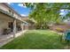 Spacious backyard with lush green grass, mature trees, patio, and a seating area perfect for entertaining at 10385 Grassyrock Ct, Las Vegas, NV 89129