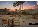 Outdoor patio area with seating, a fire pit, and tropical palm trees under a colorful sunset sky at 125 E Harmon Ave # 2318, Las Vegas, NV 89109