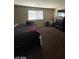 View of carpeted bedroom with lots of items on the floor plus a window and furnishings at 2409 W Gilmore Ave, North Las Vegas, NV 89032