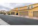 Street view featuring tan townhomes with private garages and brick driveways in a well-maintained community at 2878 Starling Summit St, Henderson, NV 89044