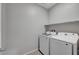 A bright laundry room with new white appliances and a single storage shelf at 378 Hellebores Ave, North Las Vegas, NV 89084