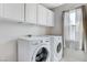 Bright laundry room with white cabinets, a window and a washer and dryer at 5513 Nickel Ridge Way, Las Vegas, NV 89122