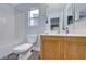 Bright bathroom features a shower-tub, toilet, window, vanity with white countertop, and wood-colored cabinets at 5527 Breecher Ave, Las Vegas, NV 89131