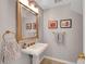 Elegant powder room with a pedestal sink, decorative mirror, and stylish fixtures at 5712 Almocita Ct, Las Vegas, NV 89141