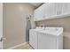 Efficient laundry room with modern white washer and dryer units and ample cabinet space at 6647 Rego Park Ct, Las Vegas, NV 89166