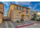 Inviting two-story tan home with a one-car garage, arched entry and mature landscaping at 687 Porchtown Ave, Las Vegas, NV 89183