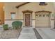 Close up of front entry and garage door of tan home with mature landscaping at 687 Porchtown Ave, Las Vegas, NV 89183