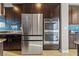 Contemporary kitchen with dark wood cabinets, granite counters, stainless steel fridge, and double ovens at 8136 Canyon Grassland St, Las Vegas, NV 89166