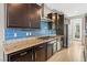 Gourmet kitchen featuring dark wood cabinetry, granite countertops, and a blue tile backsplash at 8136 Canyon Grassland St, Las Vegas, NV 89166
