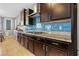 Modern kitchen featuring dark wood cabinets, granite countertops, and a stylish blue tile backsplash at 8136 Canyon Grassland St, Las Vegas, NV 89166