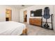 Bedroom with plush gray carpet, a wooden bedframe, adjacent bathroom and a dresser with mounted flatscreen at 9526 Granville Bridge St, Las Vegas, NV 89139